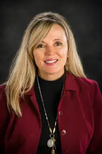 A woman in a red jacket smiling for the camera.