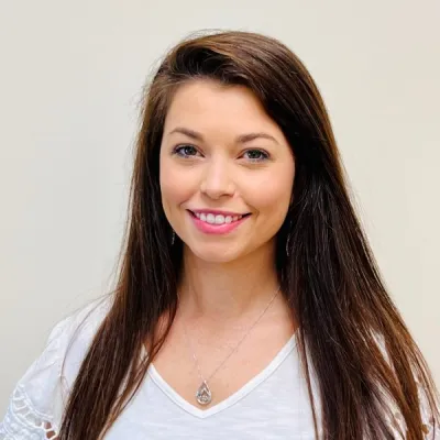 A woman with long brown hair wearing white shirt.