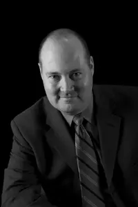 A man in suit and tie sitting down.