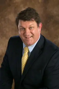 A man in suit and tie smiling for the camera.