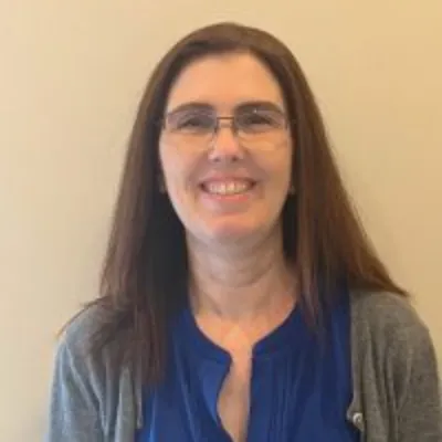 A woman with glasses smiling for the camera.