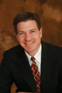 A man in suit and tie smiling for the camera.