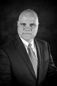 A man in suit and tie with bald head.