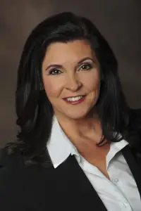 A woman with long black hair wearing a white shirt and jacket.