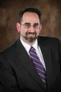 A man in a suit and tie smiling for the camera.