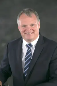 A man in a suit and tie smiling for the camera.