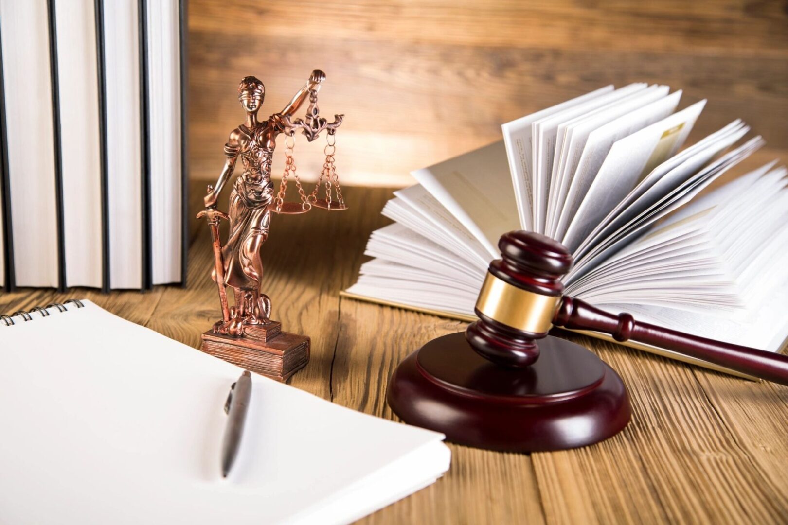 A gavel, statue of justice and papers on a table.