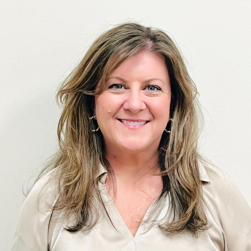Smiling woman with long hair, beige shirt.
